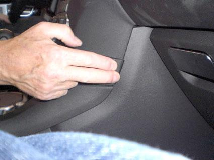 En hand trycker på en del av interiören i en Landrover Discovery.