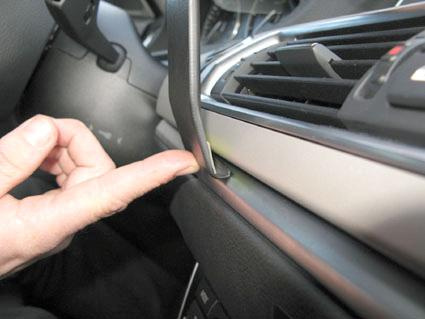 En hand som trycker på en del av bilens interiör, nära luftutloppet.