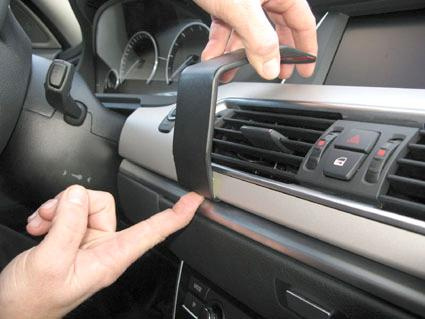 En hand visar hur man manipulerar ett luftutlopp i en BMW F07.