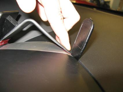 En hand pekar på ett fäste inuti en bil.