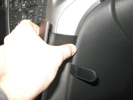 En hand som trycker på en del av bilens innervägg, nära kontroller.