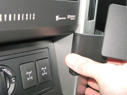 Visar en hand som trycker på en panel i en bil, eventuellt volymknapp.