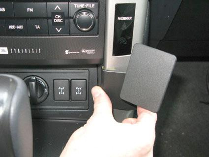 En hand som håller i en svart ventilationspanel i en bil.