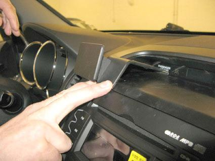 En hand visar hur man justerar en detalj i bilens interiör.