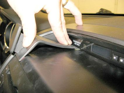 En hand lyfter en panel på instrumentbrädan i en Kia Sorento.