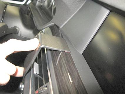 En hand pekar på ett reglage eller en del av bilens interiör.