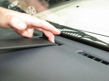 En hand justerar en del av instrumentbrädan på en bil.