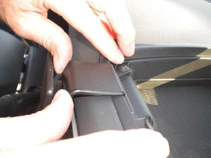 Visar en hand som justerar en del av interiören i en Dodge Caliber.