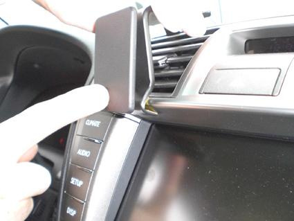 En hand justerar en del av bilens interiör, nära en skärm och kontroller.