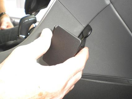 En hand håller i en vinklad komponent i ett bilinteriör.