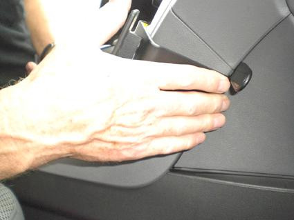 En hand som justerar en del i innersidan av en bil.