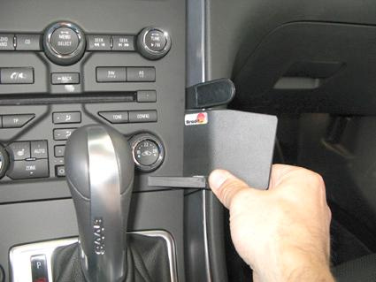 En hand håller upp en svart kort hållare nära bilens mittkonsol och växelspak.