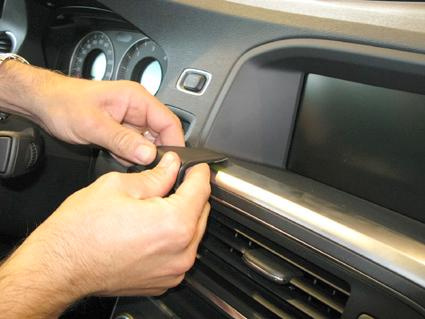 En person installerar en del i instrumentbrädan på en Volvo S60.