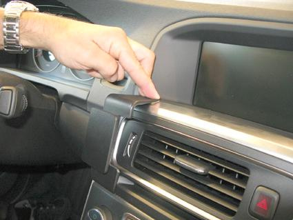 En hand trycker på en knapp på instrumentpanelen i en Volvo S60.