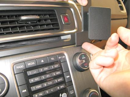 En hand visar en del av bilens instrumentbräda med kontroller.