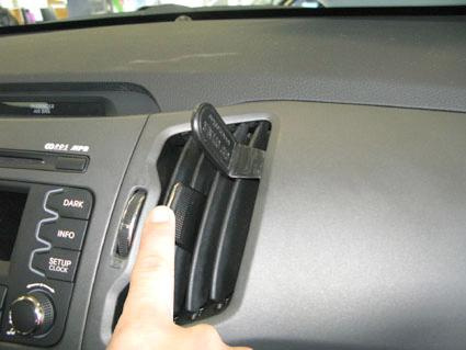 En hand trycker på en ventilationsöppning i en bilinteriör.