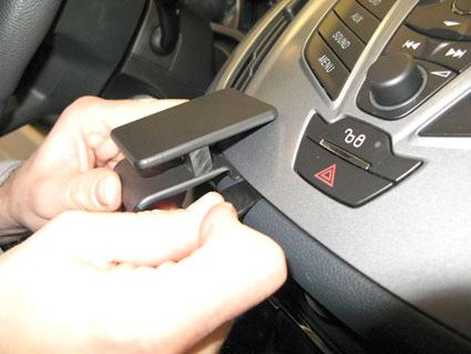 En person fäster en bildel på instrumentpanelen.