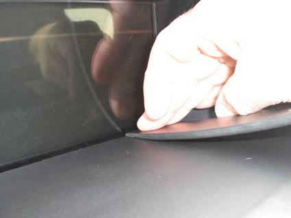 En hand justerar en gummitätning på en bils vägg.