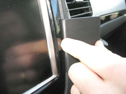 En hand trycker på en svart del i en bilinterior.