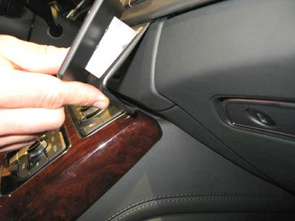 En hand fäster en vinklad monteringsbygel vid Audi A8:s instrumentpanel.