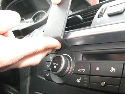 En hand justerar en ratt eller reglage i BMW X3:s instrumentpanel.