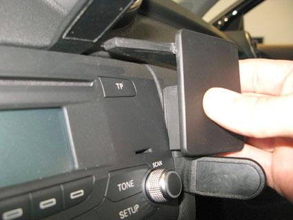 En hand som fäster en plastdel på bilens instrumentpanel.