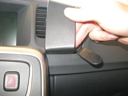 En hand som håller i en vinklad, svart detalj i en bilinteriör.