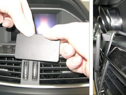 En hand håller en svart enhet som placeras i bilens ventilationssystem.