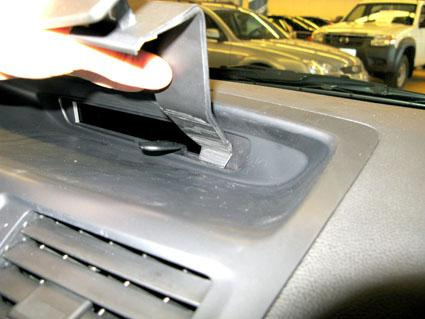 En hand placerar en del i instrumentpanelen på en Mazda 5 11-15.