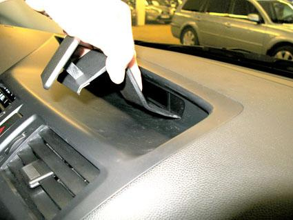 En hand tar bort en del från bilens mittkonsol.