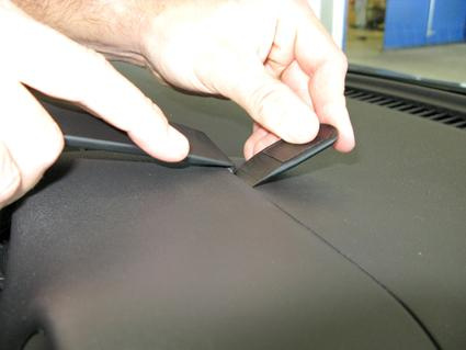 Två händer installerar en del på instrumentbrädan i en Nissan Micra.