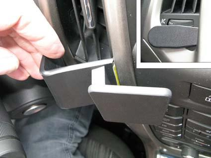 En hand som visar en bilcenterkonsol med en avtagbar hållare.