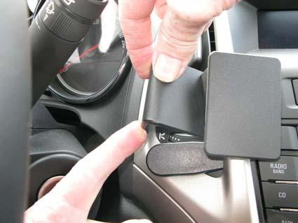 En hand placerar en hållare vid bilens centrumkontroll.