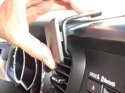 En hand installerar en detalj vid bilens instrumentpanel.