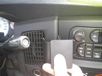 En hand som håller en svart plastdel nära bilens instrumentpanel.