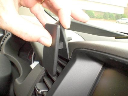 En hand håller en del som monteras på bilens luftventil.