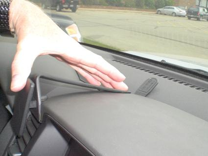 En hand som pekar på en del av instrumentbrädan i en Nissan Pathfinder.