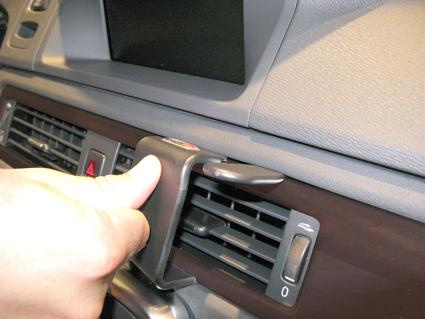 Hand som justerar ventilationsgaller i en bil med träpanel.