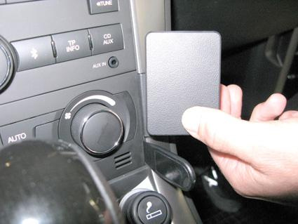 En hand visar en svart panel vid bilens kontrollpanel.