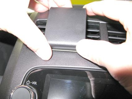 En hand placerar något på en bils instrumentbräda.