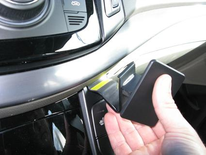 En hand håller i en vinklad hållare i en bilinteriör.