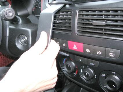 En hand justerar kontrollpanelen i en Fiat Doblo 10-14.