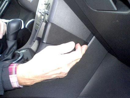 En handtrycker på en del av instrumentpanelen i en bil.