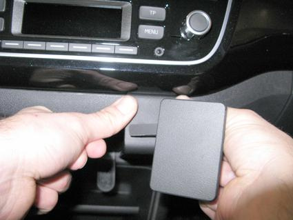 En man fäster en vinklad monteringsbygel i en bils instrumentpanel.