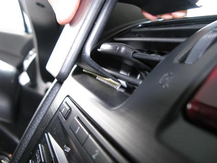 En hand installerar en del i bilens instrumentpanel.