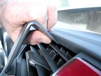 En hand installerar en monteringsbygel i en bils luftventil.