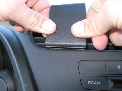 En hand sätter en svart monteringsbygel på bilens luftventil.