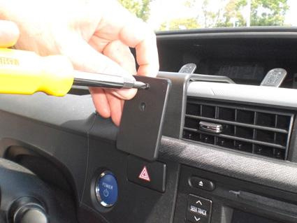 En hand fäster en monteringsbygel i en bils instrumentpanel.