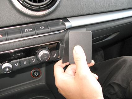 En hand håller en svart del nära bilens instrumentpanel.