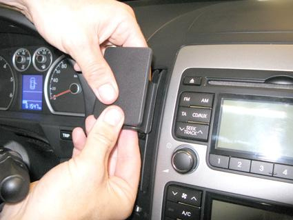 En person installerar en komponent i en bilinteriör.